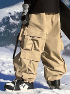 Men's snow pants by Les Odettes, Keep Money Mountain Chill Baggy style, showing the relaxed fit, durable fabric, and snowy outdoor setting.