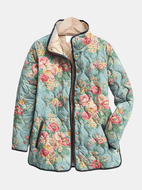Les Odettes Eliza™ quilted floral print jacket with textured quilting and vibrant flower patterns, displayed on a hanger.