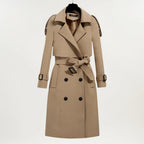 Les Odettes Ashly™ longline trench coat in beige, featuring classic lapels and a belted waist, stylishly displayed on a model.