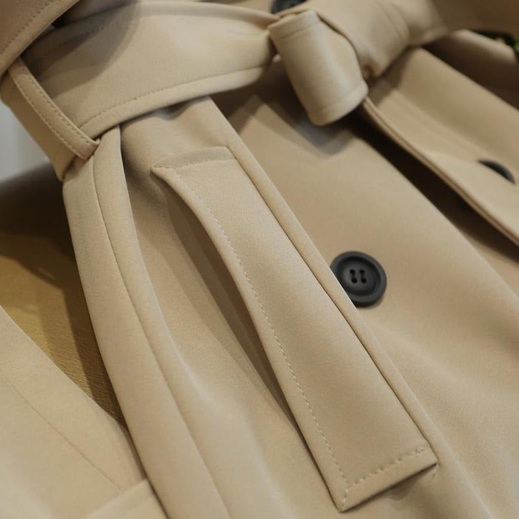 Les Odettes Ashly™ longline trench coat hanging on a rack, featuring classic collar, belt, and tailored silhouette.