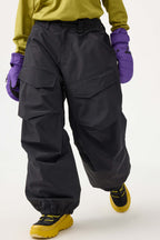 Women's black baggy utility snow pants by Les Odettes with wear-resistant fabric and adjustable waistband, shown on a hanger.