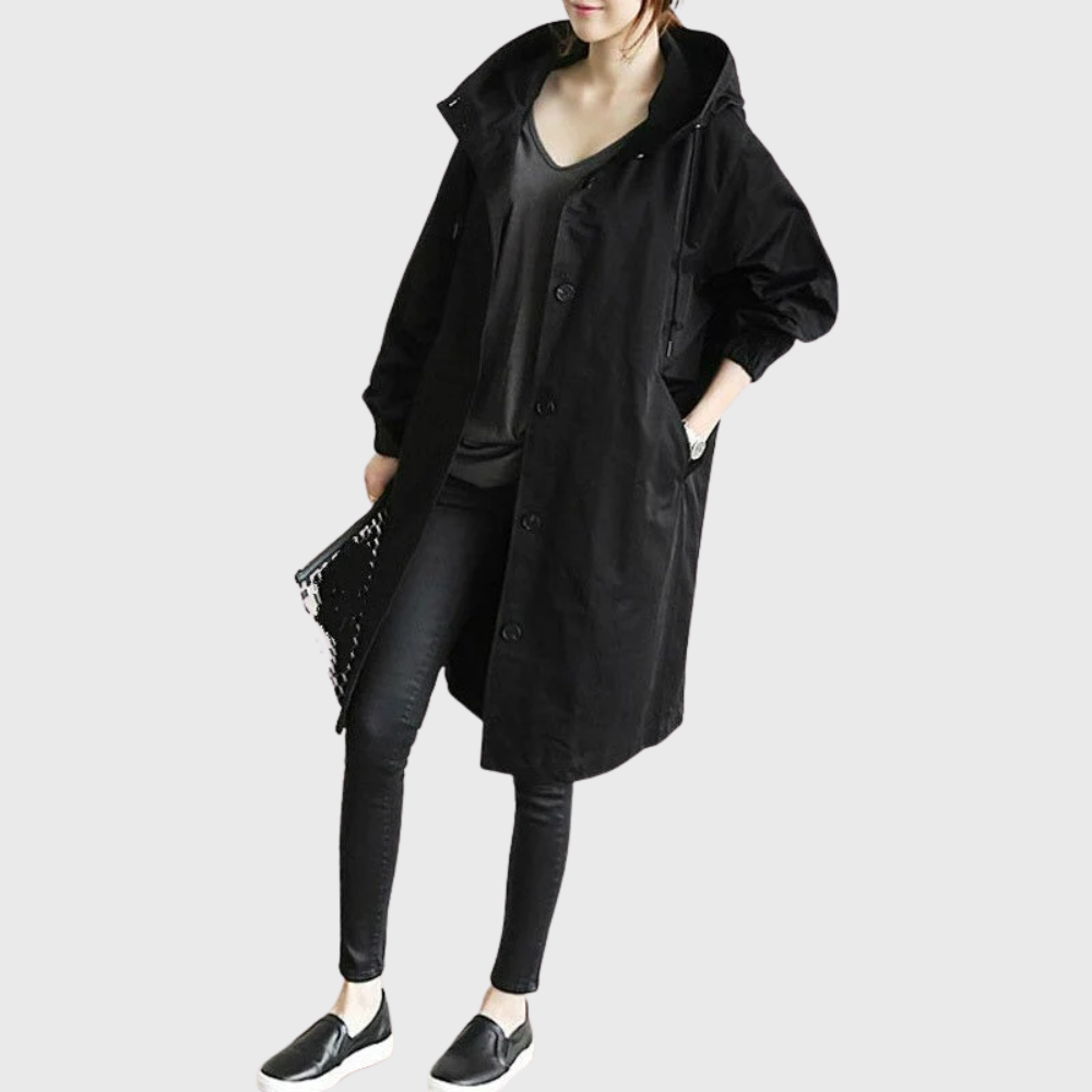 Black Arline™ waterproof trench coat by Les Odettes displayed on a hanger, showing classic design and waterproof fabric detail.