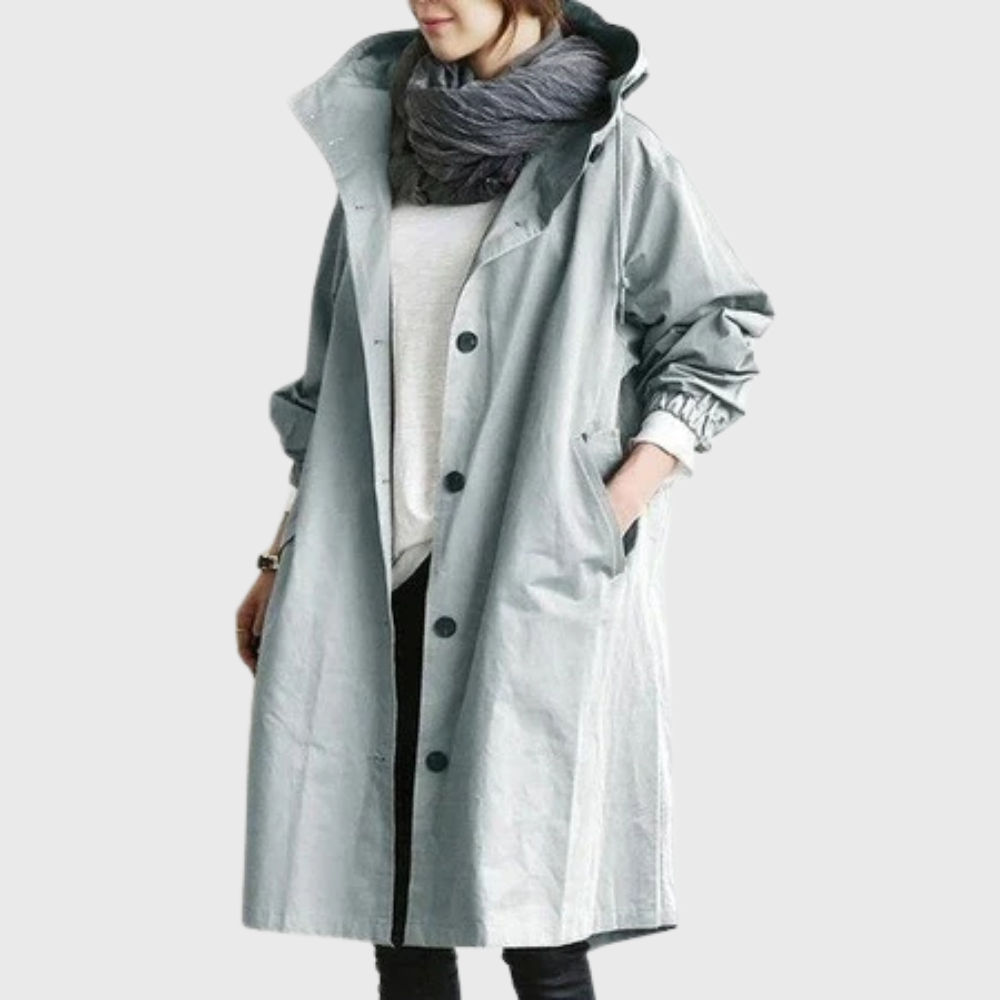 Les Odettes Arline™ waterproof trench coat hanging on a rack, featuring classic design with a belted waist and durable fabric.