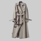 Les Odettes Aleah™ classic trench coat in beige fabric, featuring a double-breasted design and belted waist, displayed on a hanger.