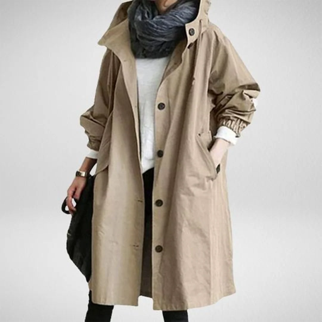 Women’s khaki waterproof raincoat with hood, lightweight design, from Les Odettes, shown hanging outdoors in the rain.